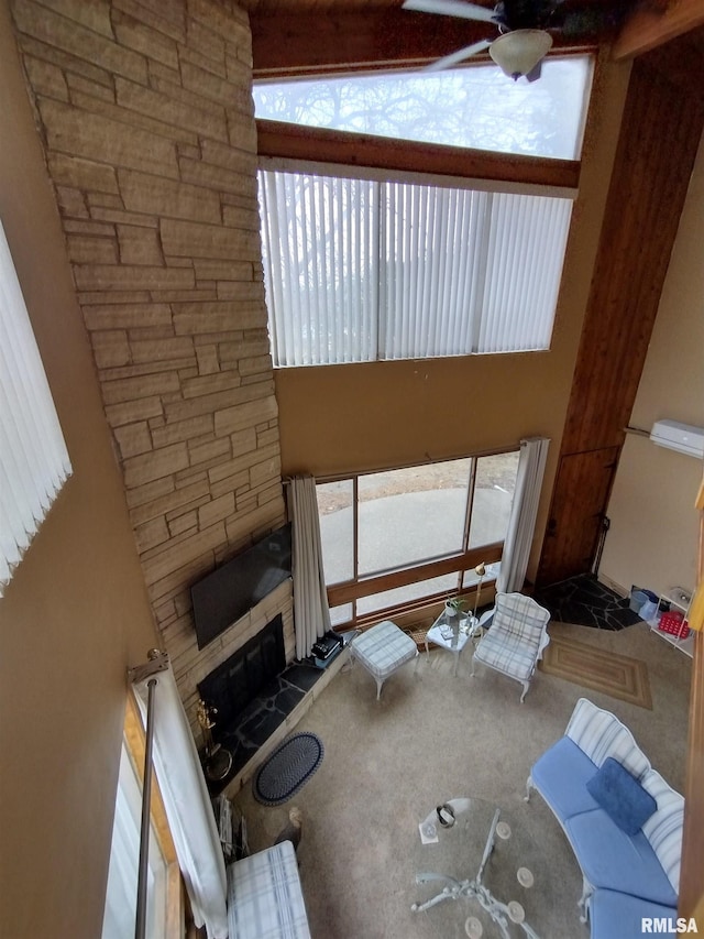 living area with a fireplace with raised hearth, ceiling fan, and a towering ceiling