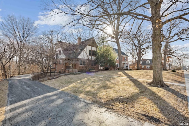 view of front of house with brick siding, a chimney, and a front yard