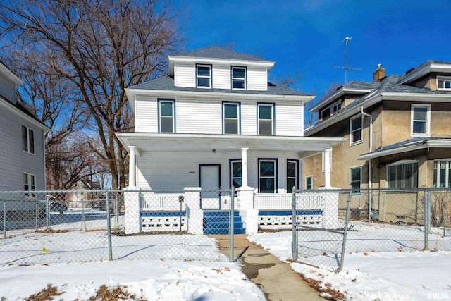 american foursquare style home with a fenced front yard, a porch, and a shingled roof