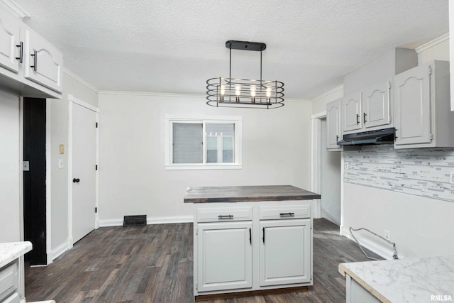 kitchen with under cabinet range hood, wooden counters, white cabinets, and pendant lighting