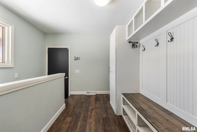 mudroom featuring a textured ceiling, dark wood-style floors, visible vents, and baseboards