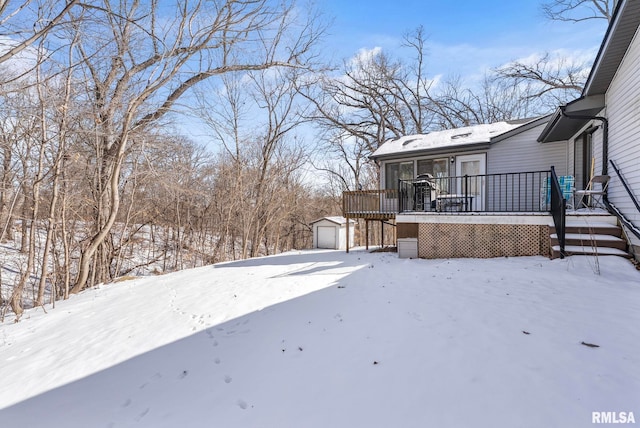 snowy yard with an outdoor structure, a deck, and a detached garage