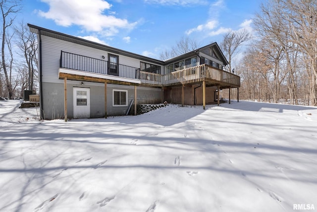 snow covered house featuring a wooden deck