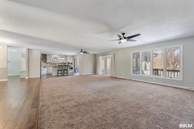 unfurnished living room featuring ceiling fan, visible vents, and baseboards