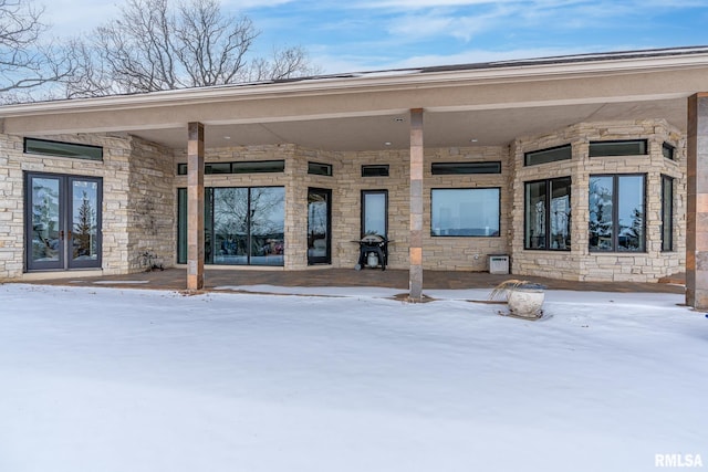 snow covered property entrance featuring stone siding