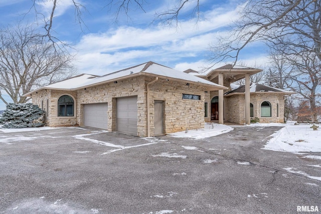 view of front of property featuring a garage, stone siding, and aphalt driveway