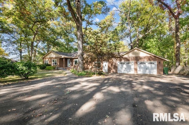 ranch-style home featuring an attached garage and aphalt driveway