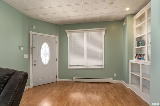 foyer entrance with light wood-style flooring, a baseboard heating unit, and baseboards