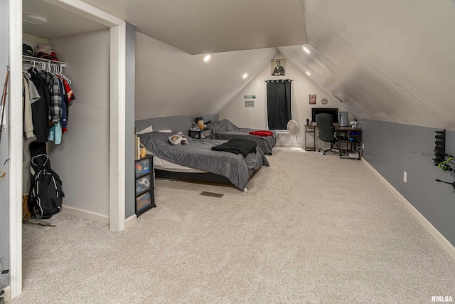 bedroom featuring baseboards, vaulted ceiling, a walk in closet, and light colored carpet