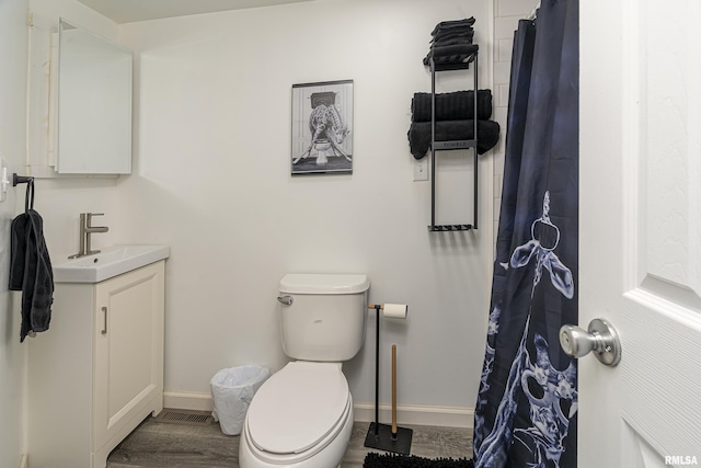 full bathroom with toilet, wood finished floors, vanity, and baseboards