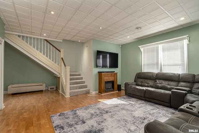 living area with a fireplace, recessed lighting, stairway, wood finished floors, and baseboards