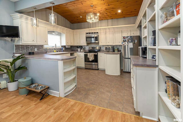 kitchen with dark countertops, appliances with stainless steel finishes, pendant lighting, open shelves, and a sink