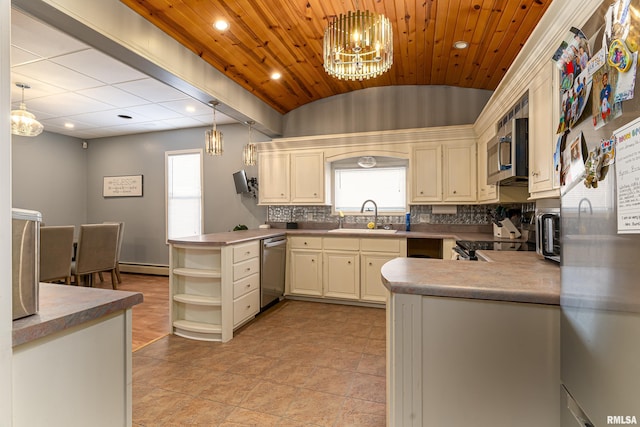 kitchen with a peninsula, appliances with stainless steel finishes, pendant lighting, and a sink