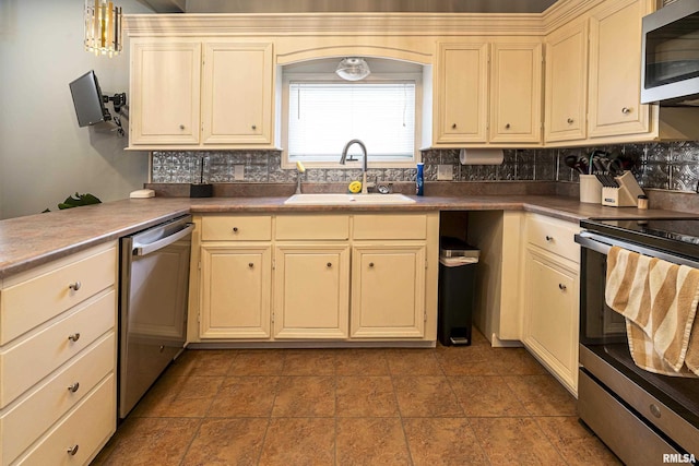 kitchen featuring cream cabinets, stainless steel appliances, a sink, backsplash, and pendant lighting