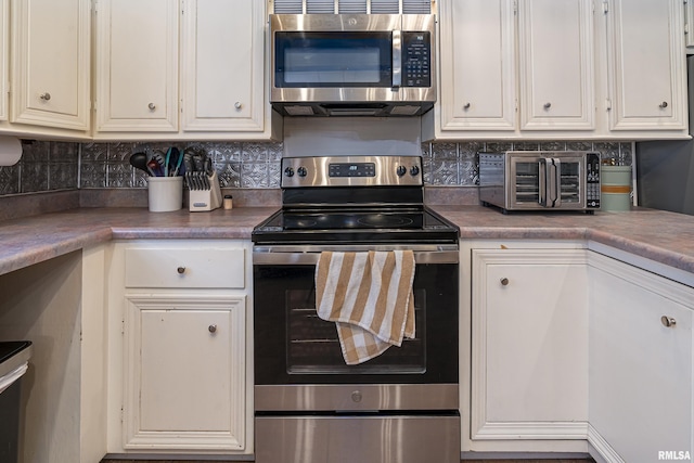 kitchen with appliances with stainless steel finishes, a toaster, backsplash, and white cabinetry