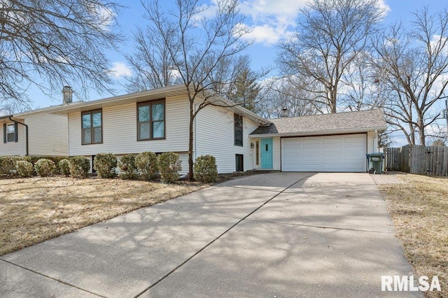 view of front of property featuring concrete driveway, fence, and a garage