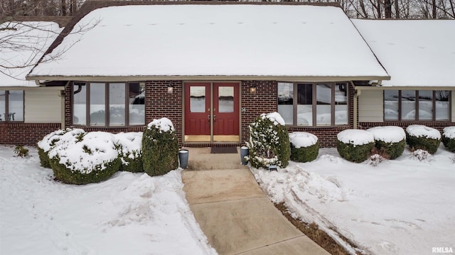 view of front of property featuring a sunroom, french doors, and brick siding