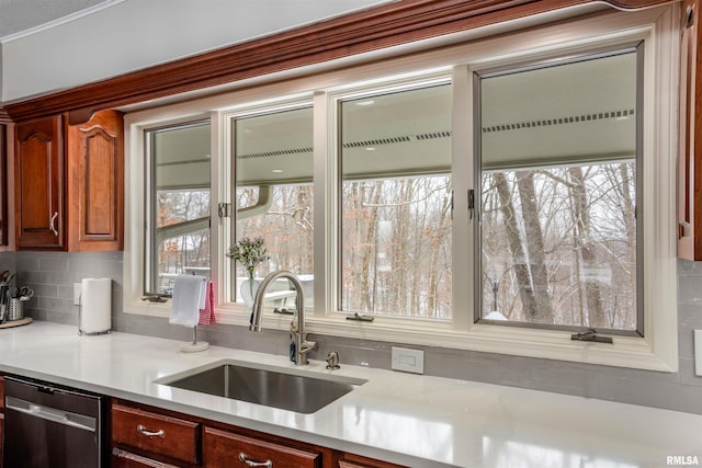 kitchen with dishwasher, light countertops, a sink, and decorative backsplash