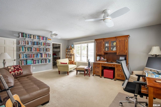 office space with light colored carpet, ceiling fan, and a textured ceiling