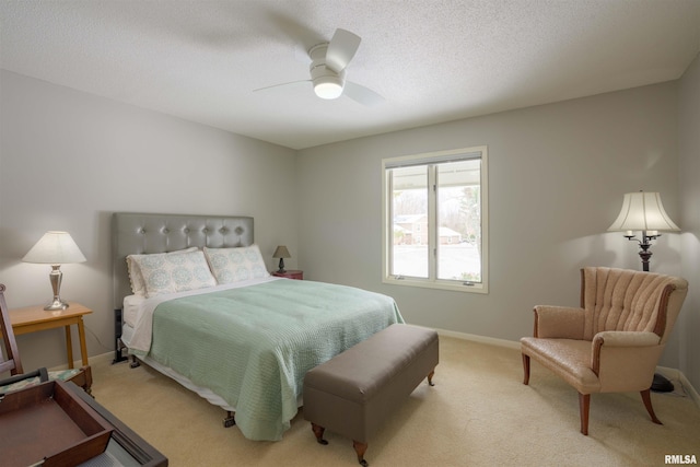 bedroom with ceiling fan, baseboards, a textured ceiling, and light colored carpet