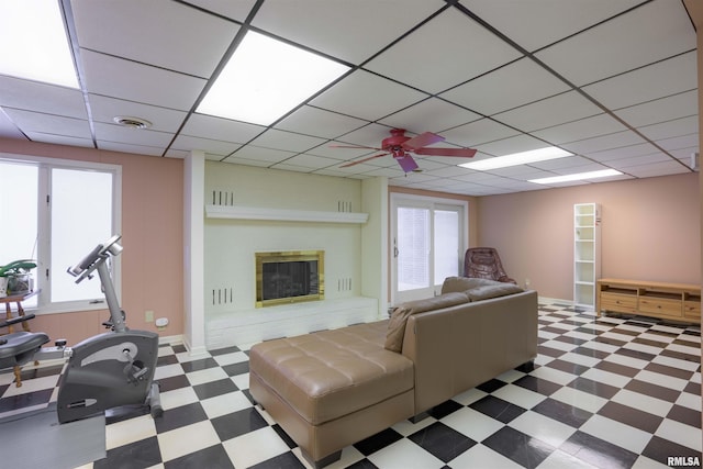 living room with ceiling fan, a drop ceiling, a fireplace, visible vents, and tile patterned floors