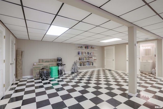 finished below grade area with baseboards, a paneled ceiling, and tile patterned floors