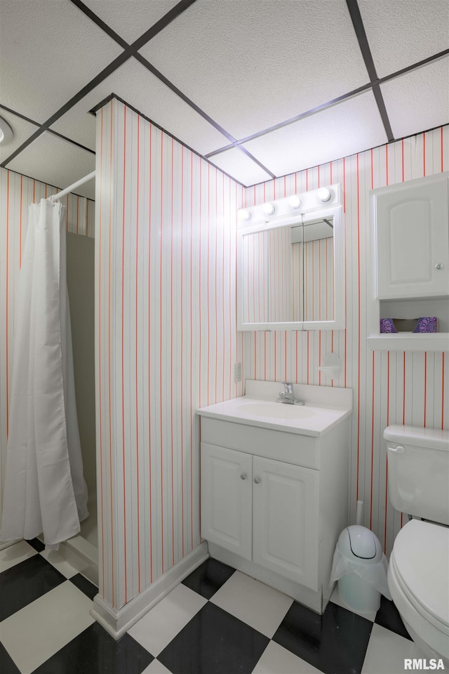 bathroom with a shower with shower curtain, toilet, vanity, a drop ceiling, and tile patterned floors