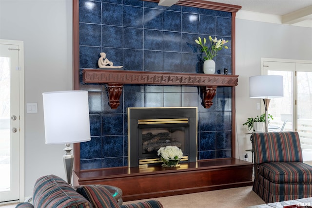 carpeted living room with ornamental molding and a tile fireplace