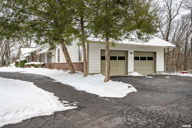 snow covered garage featuring aphalt driveway