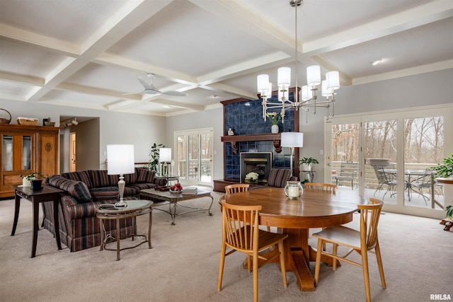 dining room with light carpet, ceiling fan with notable chandelier, coffered ceiling, beamed ceiling, and a tiled fireplace