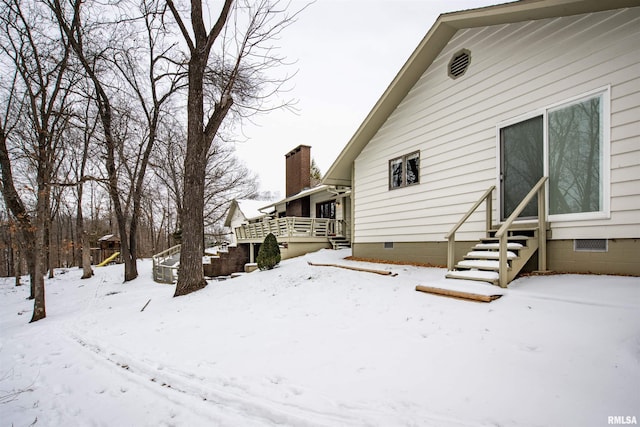 snow covered back of property featuring crawl space, a deck, and entry steps