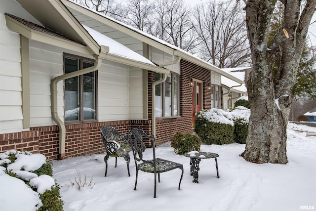 view of snow covered exterior featuring brick siding