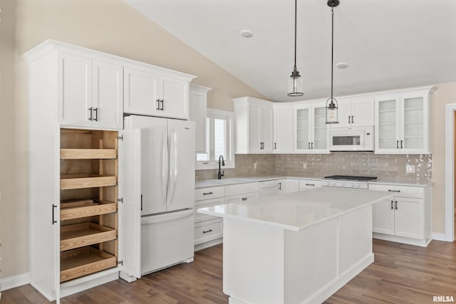 kitchen with white appliances, light countertops, hanging light fixtures, a center island, and glass insert cabinets