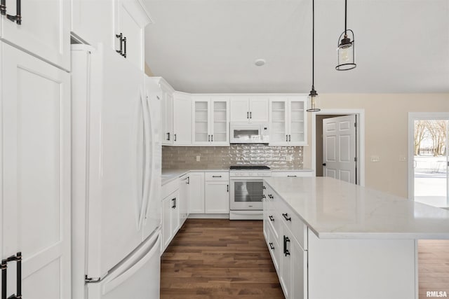 kitchen with white appliances, glass insert cabinets, a center island, light stone countertops, and white cabinetry