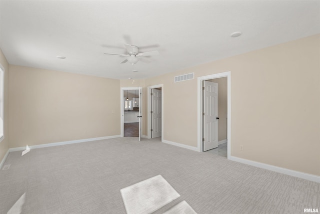 unfurnished bedroom featuring light carpet, a ceiling fan, visible vents, and baseboards