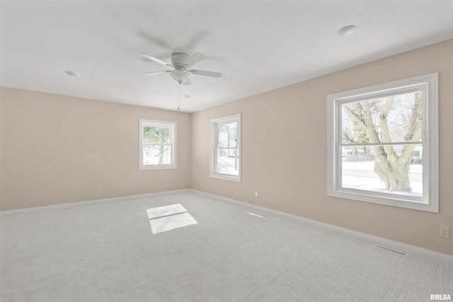 empty room featuring visible vents, light carpet, ceiling fan, a textured ceiling, and baseboards