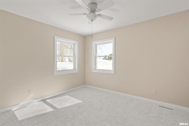 empty room featuring ceiling fan, light carpet, visible vents, and baseboards