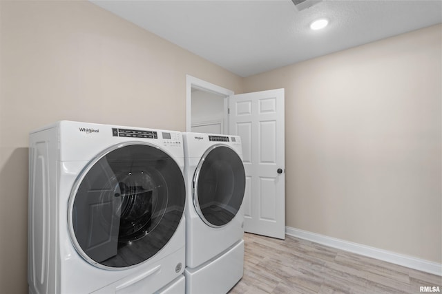 laundry room with laundry area, washing machine and dryer, baseboards, and light wood-style flooring