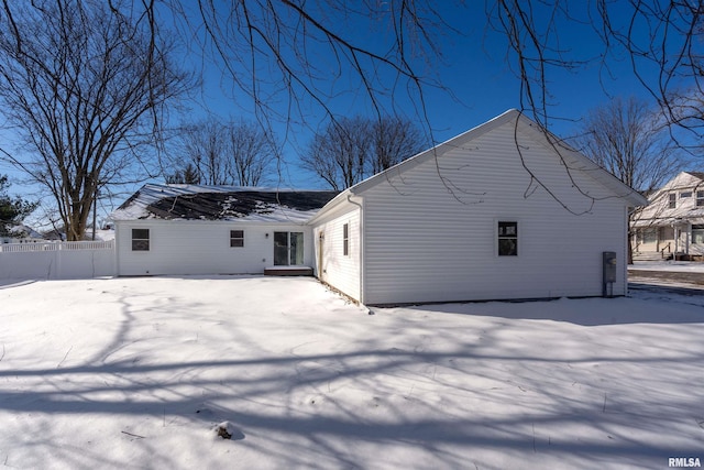 snow covered house featuring fence