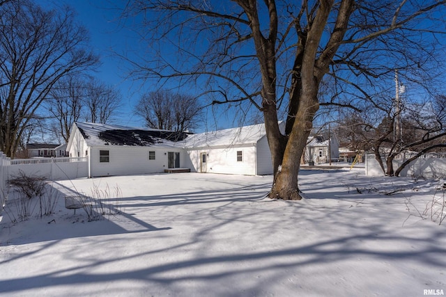 snow covered rear of property featuring fence