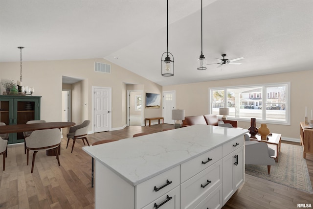 kitchen featuring visible vents, white cabinets, open floor plan, hanging light fixtures, and a center island