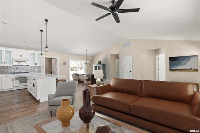 living area with a ceiling fan, dark wood finished floors, visible vents, and vaulted ceiling