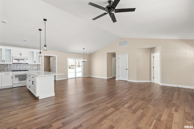 interior space featuring lofted ceiling, ceiling fan with notable chandelier, dark wood-style flooring, visible vents, and baseboards