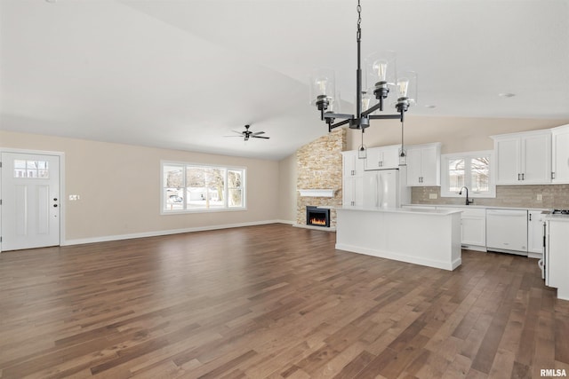 kitchen with white appliances, white cabinets, open floor plan, light countertops, and a center island