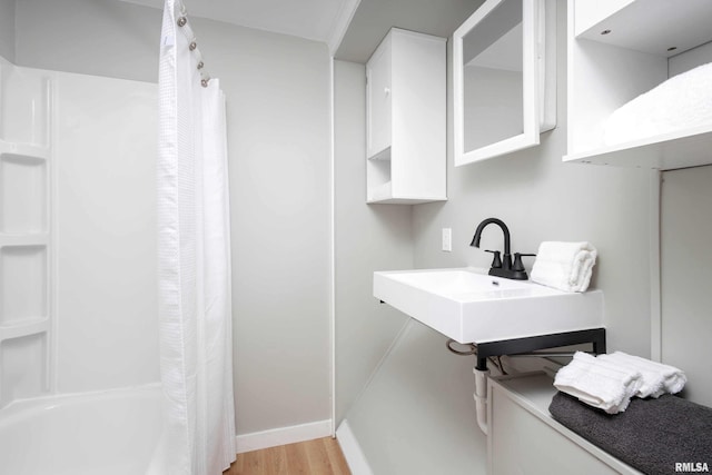 full bathroom with wood finished floors and baseboards