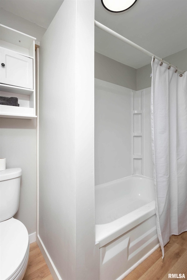 bathroom featuring shower / bath combo with shower curtain, baseboards, toilet, and wood finished floors