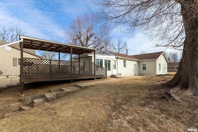 rear view of house featuring fence and a deck