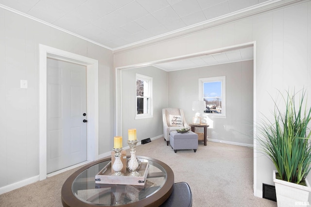 sitting room featuring carpet floors, crown molding, and baseboards