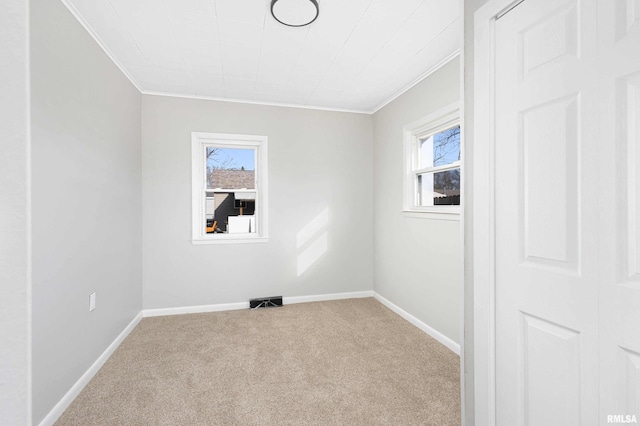 empty room featuring carpet floors, a wealth of natural light, visible vents, and baseboards