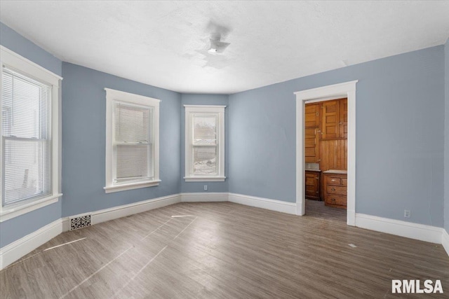 interior space with visible vents, a textured ceiling, baseboards, and wood finished floors